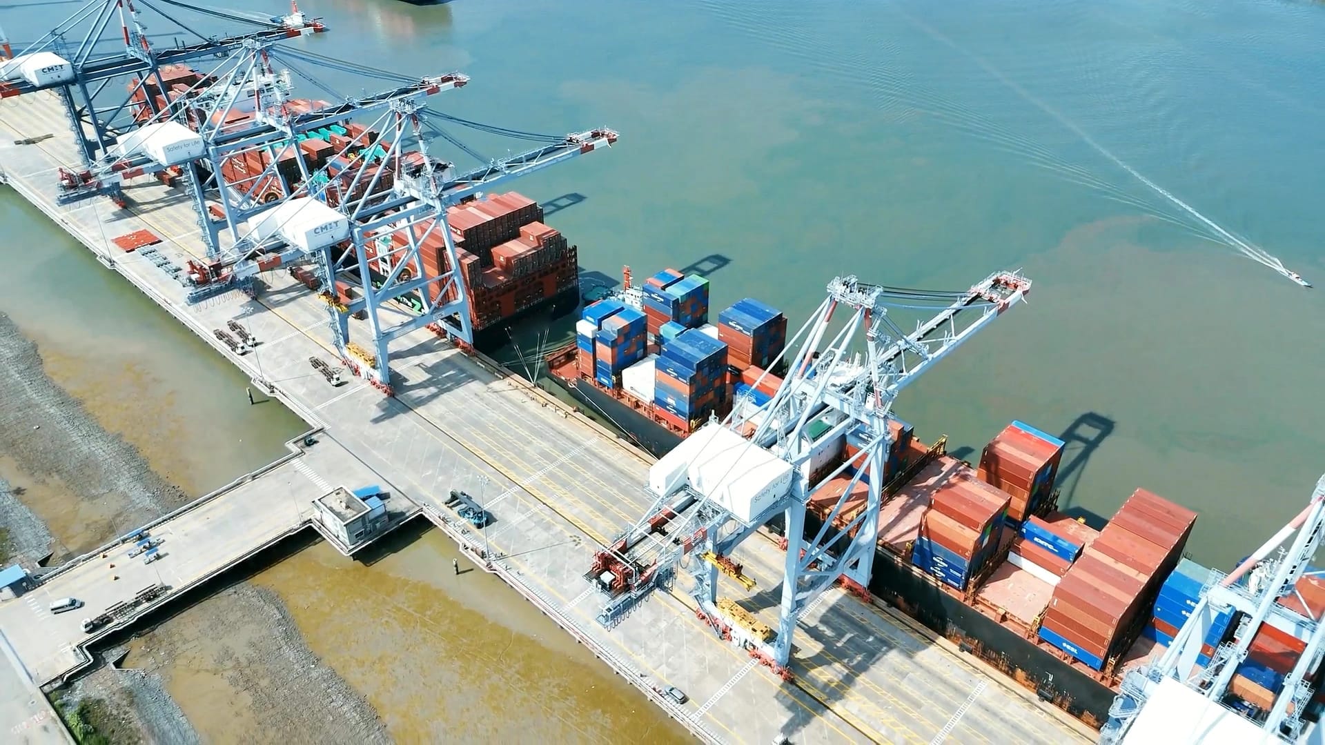 Aerial view of a container terminal, with ship-to-shore cranes working a vessel