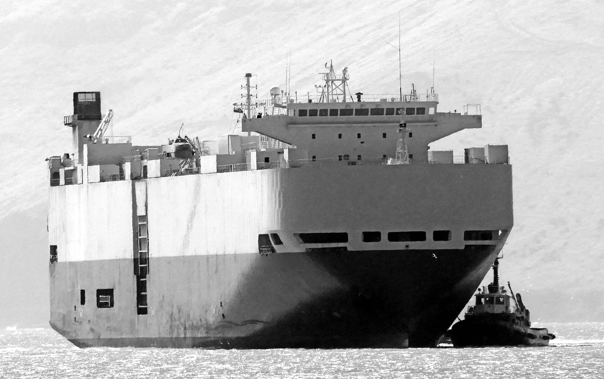 Ocean-going car carrier escorted by a tug